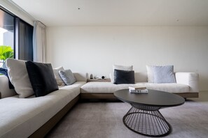 Ein modernes Wohnzimmer mit einem Ecksofa, einem runden Couchtisch und einem großen Fenster.