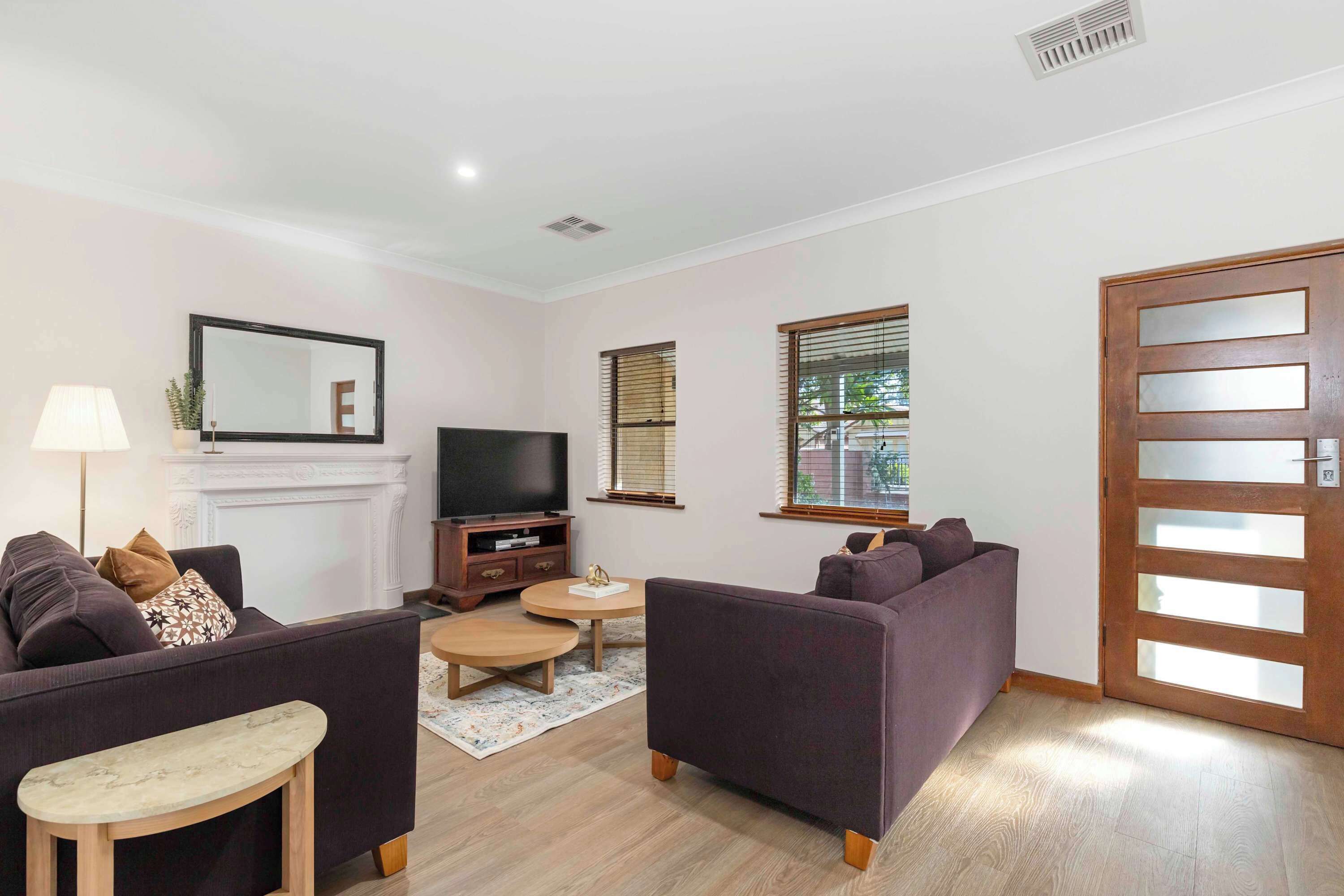 A living room with two sofas, a TV, a fireplace, and a door with frosted glass panels.