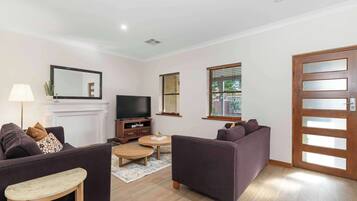 A living room with two sofas, a TV, a fireplace, and a door with frosted glass panels.