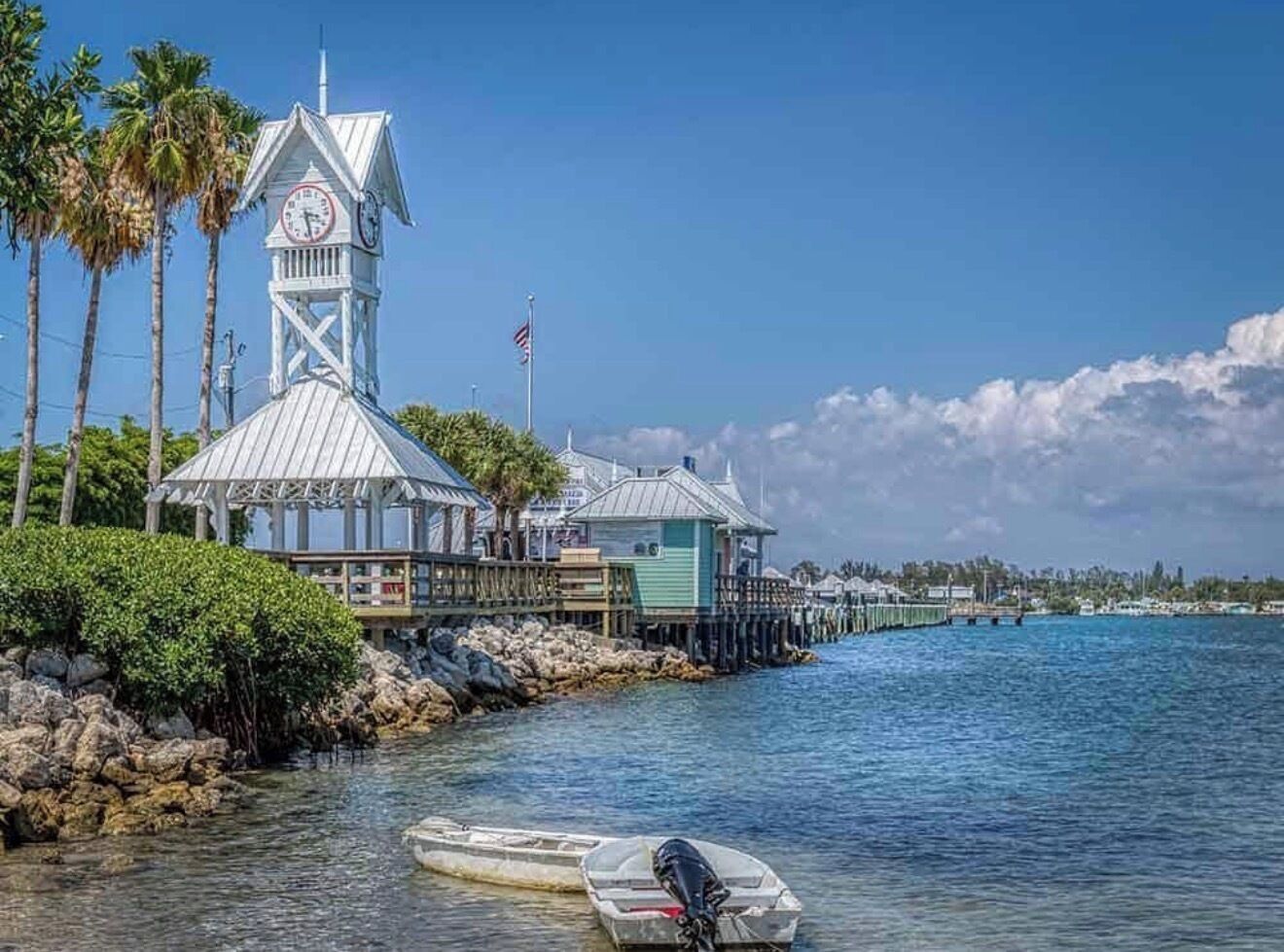 A waterfront building with a clock tower, docked boats, and a clear blue sky.