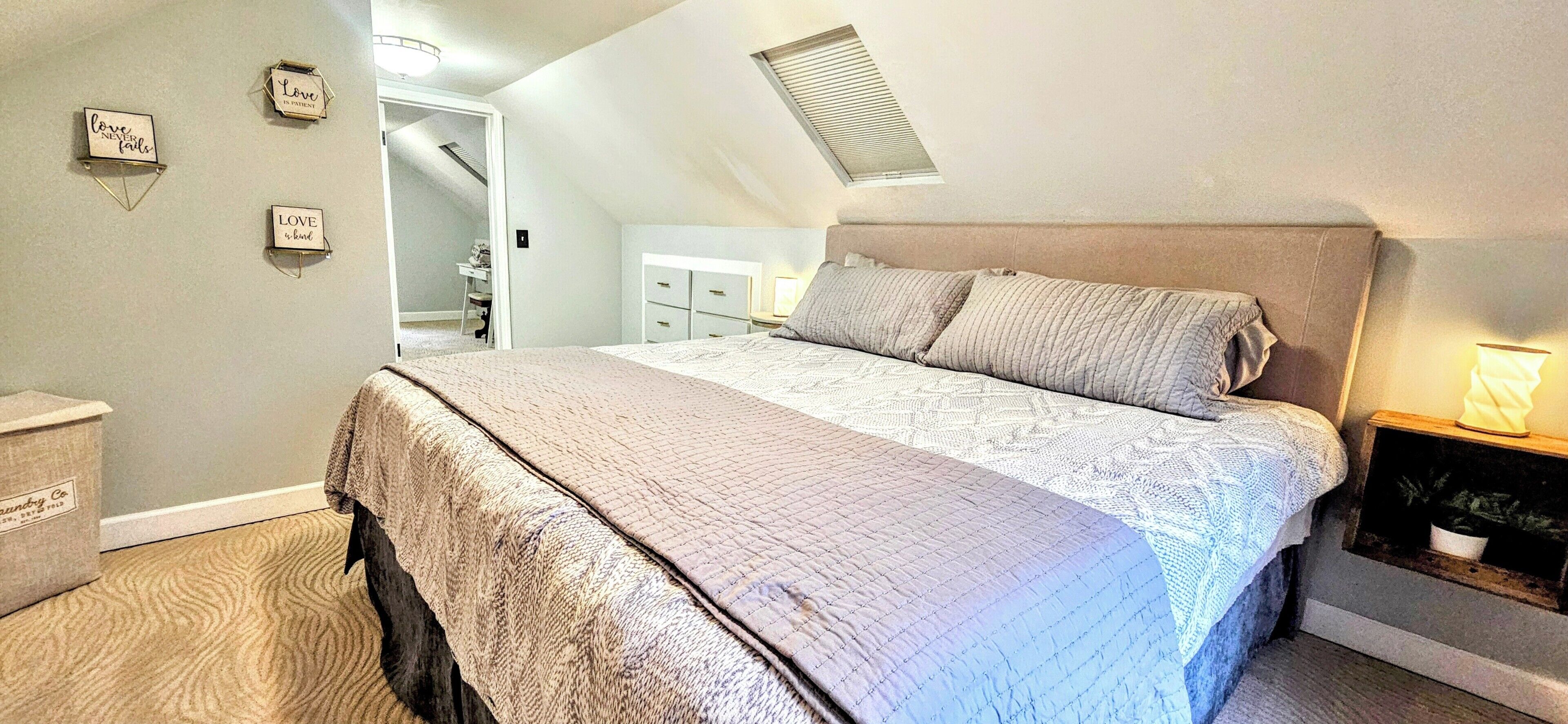 Un dormitorio con cama, mesita de noche, cómoda, escritorio y silla.