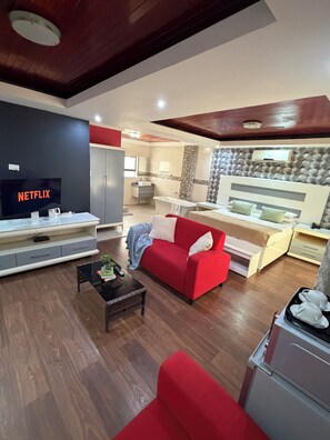 Een moderne woonkamer met een rode bank, een televisie en een keuken met een inbouwoven.