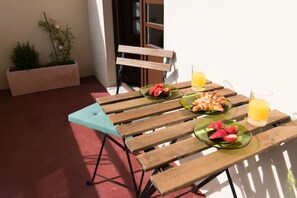 A wooden table with breakfast items, including croissants and strawberries, and a glass of orange juice. - GuestReady - Rivoli Apartment with Balcony (Porto)