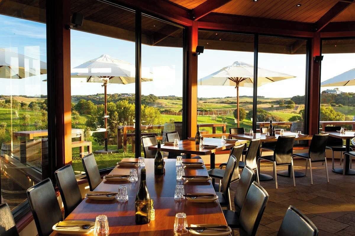 Un espace extérieur aménagé pour les repas, avec des tables et des chaises, de grands parasols et une vue sur une montagne.