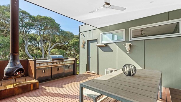Een terras met een barbecue, een tafel en een plafondventilator.