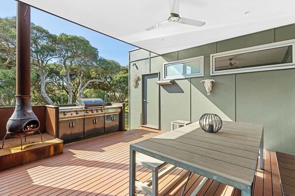 Eine Terrasse mit Grill, Tisch und Deckenventilator.