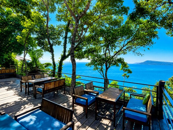 Una terraza de madera con asientos exteriores y vista al mar.