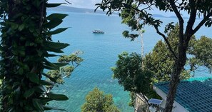 Vista de un cuerpo de agua con un bote, rodeado de árboles y un edificio con techo de tejas.