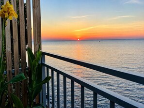 Eine Holzwahlhecke mit Blick auf ein ruhiges Meer bei Sonnenuntergang.