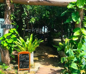 Zona de café al aire libre con una pizarra anunciando ofertas de hora feliz con cócteles y cerveza.
