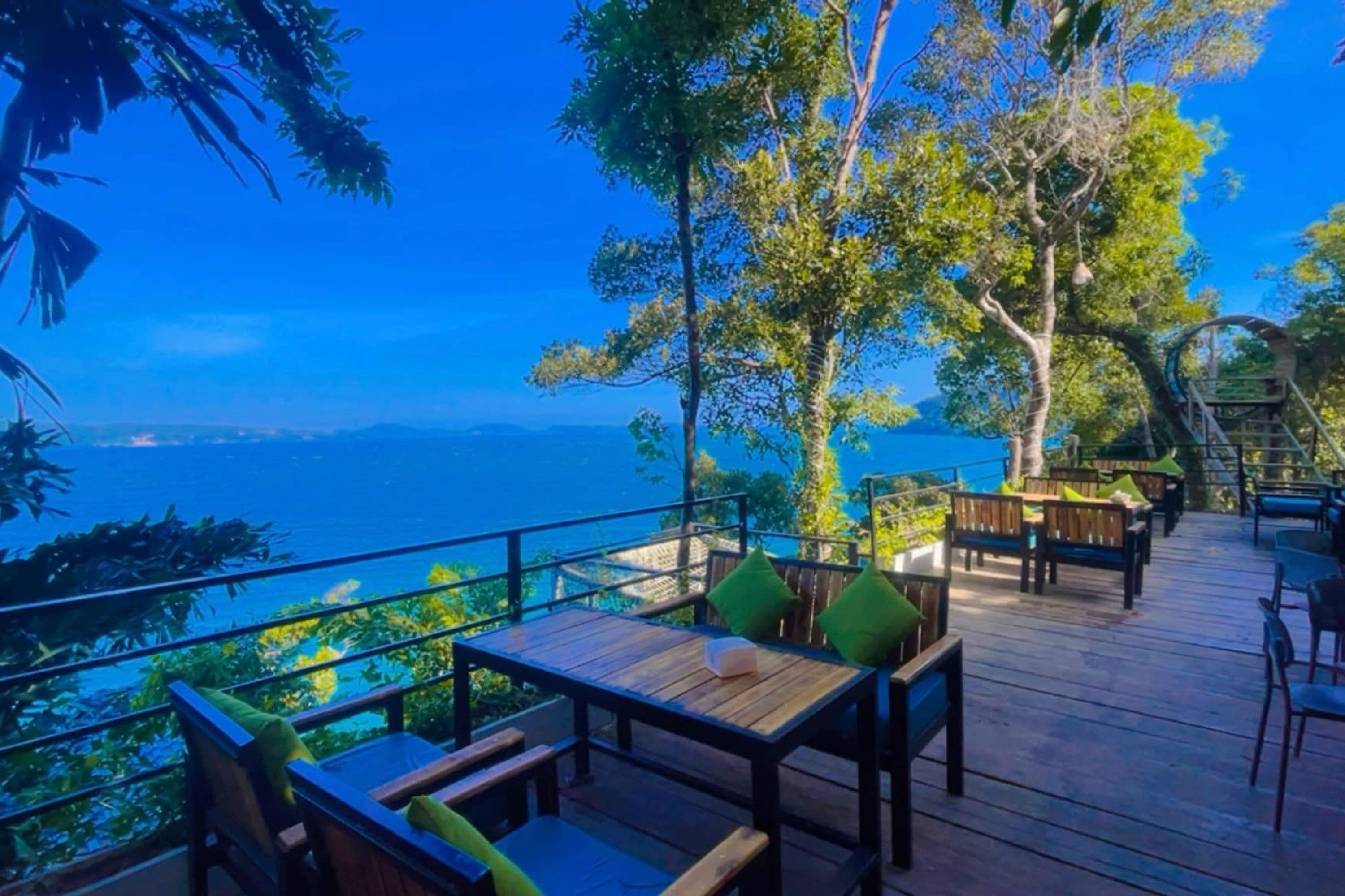 Una terraza exterior con mobiliario de madera y vista al mar.