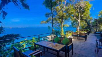 Una terraza exterior con mobiliario de madera y vista al mar.