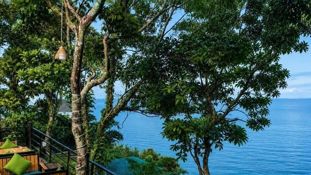 A wooden deck with outdoor seating, overlooking a body of water. - The Cliff Bungalow (Koh Rong Sanloem)