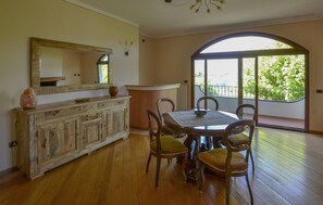 A dining area with a round table, chairs, a wooden cabinet, and a large mirror. - Beautiful apartment in Poppi with WiFi (Poppi)