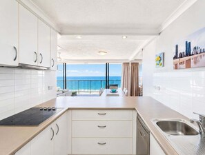A modern kitchen with white cabinets, a built-in oven, and a view of the ocean. - Beachfront Ocean Views | Pools, Spa & Tennis (Gold Coast)