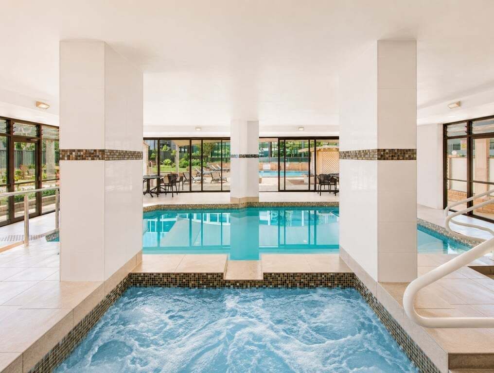 Piscina interna con acqua cristallina, circondata da colonne bianche e un bordo piastrellato.