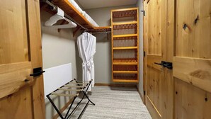 A laundry area with a drying rack, a hanging robe, and wooden shelves.
