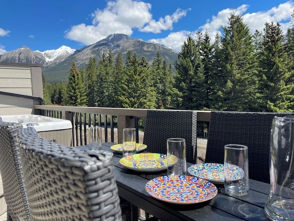 A patio with outdoor seating, a table set with plates and glasses, and a mountain view in the background.