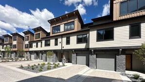 Un immeuble résidentiel moderne doté d’une allée pavée, d’aménagements paysagers en pierre et surplombant un ciel dégagé.