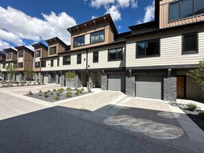 En moderne boligbygning med en belagt indkørsel, stensætning og en klar himmel.
