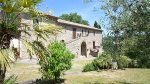 Un edificio in pietra con tetto a tegole, finestre ad arco e una piccola scala che conduce a un portico.