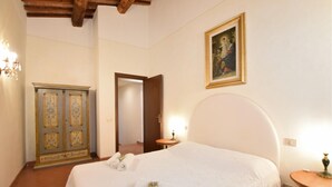 Una camera d'albergo con un letto, un armadio, un quadro e uno specchio.