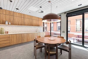 A modern kitchen with wooden cabinets, a round dining table, and a pendant light. - Parkview 903 | Brunswick 3BR by the Park, Balcony (Brunswick)