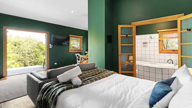Une chambre à coucher comprenant un lit, un canapé, une fenêtre et une salle de bain avec un lavabo et un miroir.