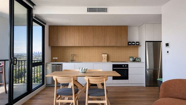 A modern kitchen with wooden cabinets, a stainless steel refrigerator, and a dining area with a table and chairs. - Brunswick 2BR 2Bath w Free Parking + Park Views (Brunswick)