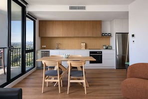Une cuisine moderne avec des meubles en bois, un réfrigérateur en acier inoxydable et un coin repas comprenant une table et des chaises.