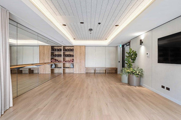 Una habitación amplia con suelo de madera, pared espejada e iluminación empotrada en el techo.