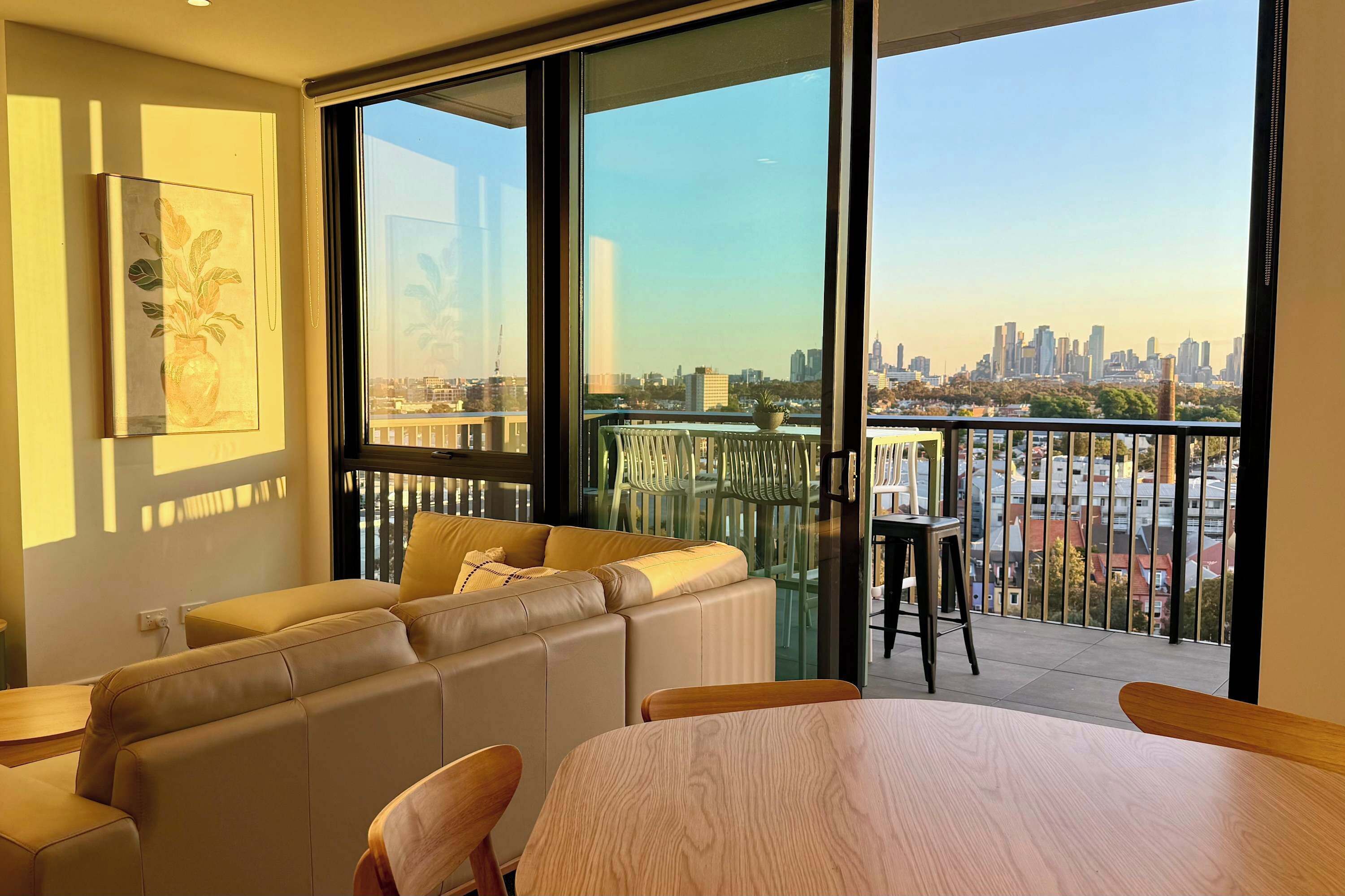 Ein modernes Wohnzimmer mit einer Couch, Sesseln, einem Esstisch und einem großen Fenster mit Blick auf die Stadt.