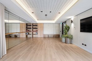 Ein geräumiger Raum mit Holzboden, einer Spiegelwand und einer Decke mit eingelassener Beleuchtung.