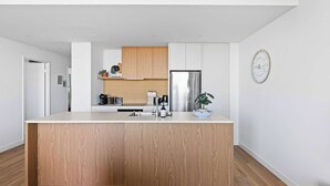 Una cocina moderna con una isla central, armarios de madera, electrodomésticos de acero inoxidable y una planta en maceta.