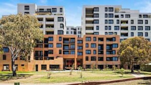 Un edificio residencial de varios pisos con un patio central, balcones y cielo despejado.