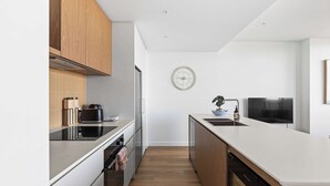 Una cocina moderna con armarios de madera, encimera blanca, horno integrado y lavavajillas.