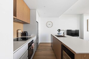 A modern kitchen with wooden cabinets, a white countertop, a built-in oven, and a dishwasher. - City View 3BR | Free Parking | Family Friendly (Brunswick)