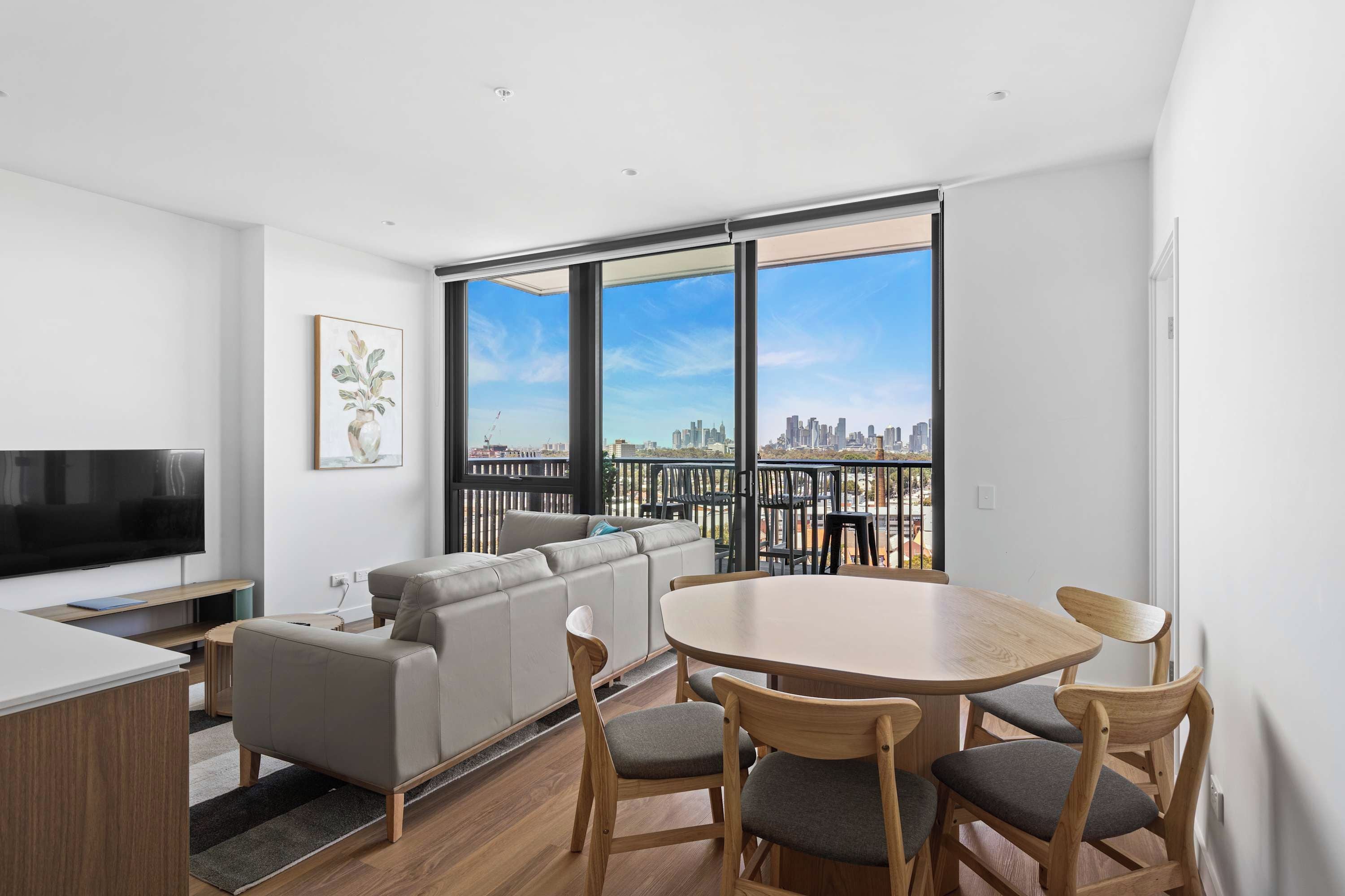 Un apartamento moderno con sala de estar, mesa de comedor y un amplio ventanal con vista a la ciudad.