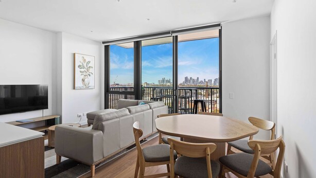 Un apartamento moderno con sala de estar, mesa de comedor y un amplio ventanal con vista a la ciudad.