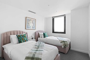 A hotel room with two beds, a window, and a framed picture on the wall. - Cityscape 901 | Top-Floor City View, Brunswick 3BR (Brunswick)