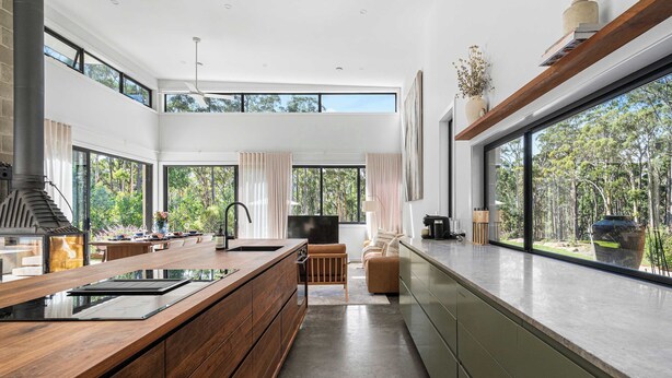 Una cocina moderna con una isla grande, electrodomésticos integrados y vistas al exterior.