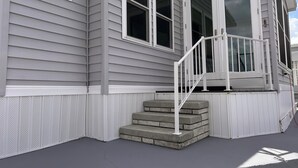 A house with a front porch, a set of steps leading to the entrance, and a garage door. - Rest Ashore on the Sarasota Bay (Bradenton)