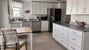 Eine moderne Küche mit weißen Schränken, einem Esstisch mit Stühlen, einem Kühlschrank und einer Mikrowelle.