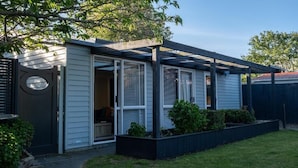 Ein Haus mit überdachter Terrasse, einer Schiebetür und einem kleinen Garten.