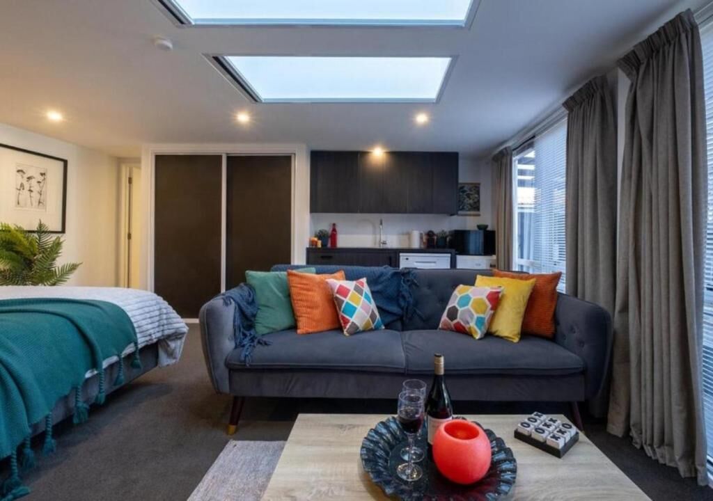 A modern living room with a sofa, a coffee table, a skylight, and a kitchen area in the background.