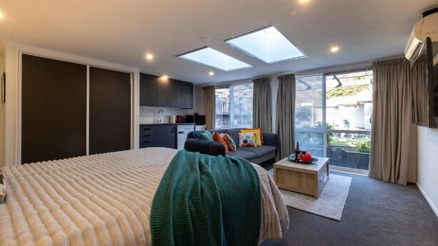 Ein Schlafzimmer mit einem großen Bett, einer Couch, einem kleinen Tisch und einem Balkon mit Blick.