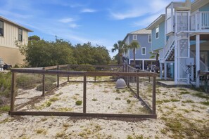 A fenced area with a sandy surface, a dome structure, and buildings in the background. - New St George Island Retreat  Pool Pet Friendly (Saint George Island)