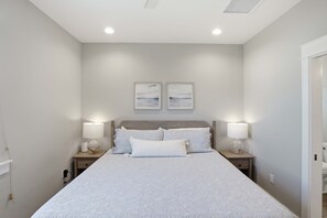 A bedroom with a large bed, two bedside lamps, and two wall-mounted picture frames. - New St George Island Retreat  Pool Pet Friendly (Saint George Island)