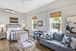 A well-lit room with a bed, a wooden chair, a sofa, and a desk with a lamp. - New St George Island Retreat  Pool Pet Friendly (Saint George Island)