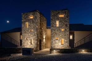 A modern building with stone facades and illuminated windows at night.